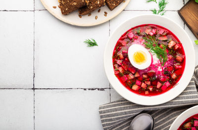 Summer cold beetroot soup with sour cream and egg on white tile background. russian cuisine. 