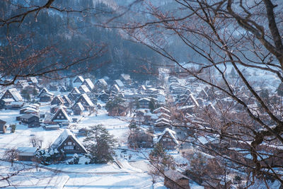 Snow covered townscape seen through bare trees