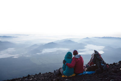 Rear view of people on snowcapped mountains against sky