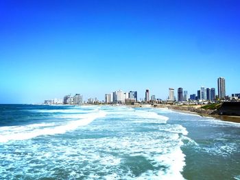 Scenic view of sea and buildings against clear blue sky