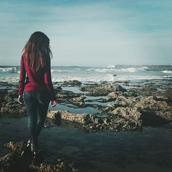 Rear view of woman standing at beach