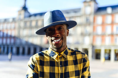 Smiling african man wearing hat while standing in city
