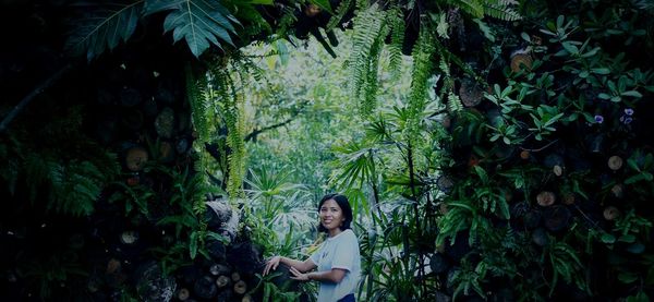 Portrait of woman standing amidst plants