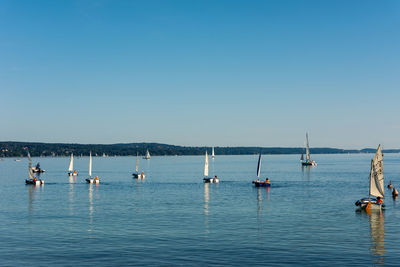 Sailboats in sea against clear blue sky