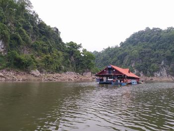 House by lake and buildings against clear sky