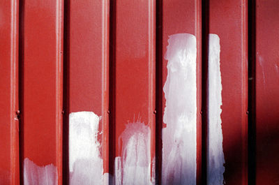 Full frame abstract shot of red metal wall with white paint.