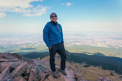 Rear view of man standing on mountain against sky