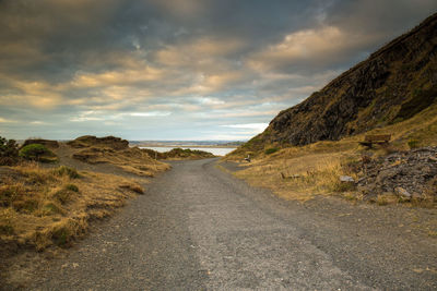 Dirt road amidst landscape against sky