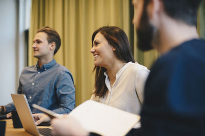 Happy businesswoman sitting with male colleagues in board room meeting