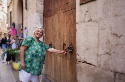 Woman opens a wooden door in a mediterranean village