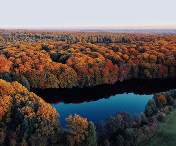 Scenic view of autumn trees by river against sky