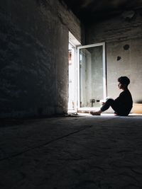 Young man using mobile phone in window