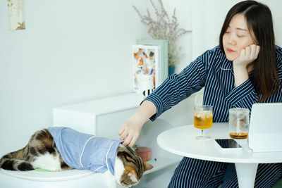 Woman in pajamas cloth drink tea and play with her cat