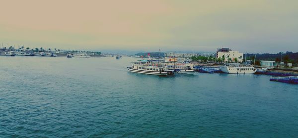 Boats moored at harbor against sky during sunset