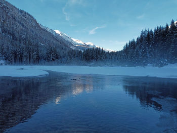 Scenic view of lake by snowcapped mountains against sky