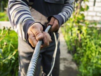 Adult caucasian male pulls cable through metal protective sleeve.