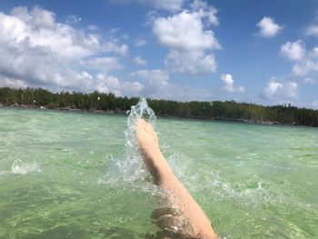 Low section of person in sea against sky