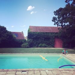 Swimming pool by trees against sky