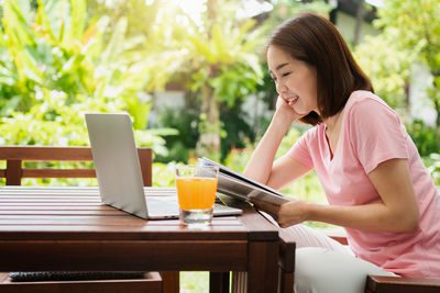 Young woman using mobile phone while sitting on table