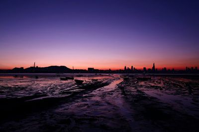 Silhouette of sea and cityscape during sunset