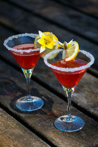 High angle view of drink garnished with yellow flower with lemon slice on wooden table