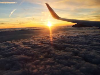 View of airplane wing over sea during sunset