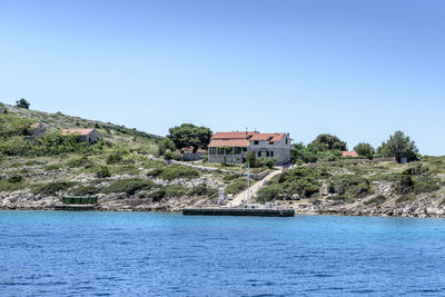 Scenic view of river by buildings against clear blue sky