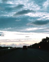 Cars on road against sky during sunset