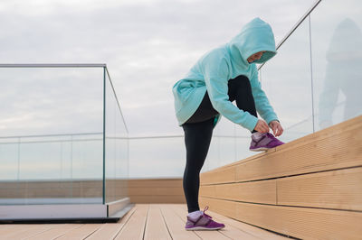 Woman tying shoelace standing outdoors