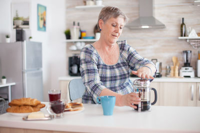 Senior woman making coffee at home