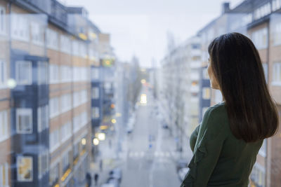 Woman looking through window at street