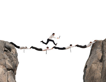 Low angle view of people on rocks against clear sky