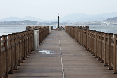 Diminishing view of wooden pier against sky