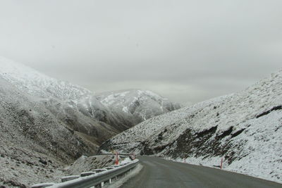 Road amidst snowcapped mountains against sky