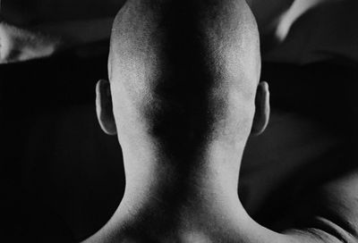 Young man from behind, shirtless, shaved head, ears and neck, listening to the world, meditation