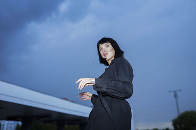 Young woman looking away against sky