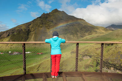 Woman looking to a rainbow over the skogafoss waterfall in iceland