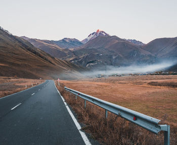 Road leading towards mountains against sky