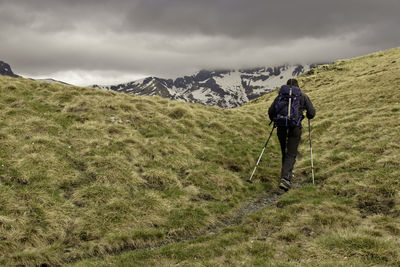 Rear view of man standing on mountain against sky