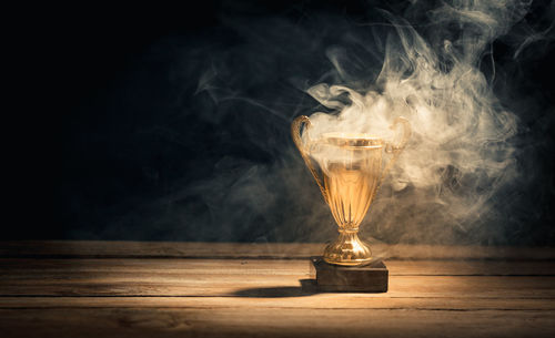 Illuminated light bulb on table against black background