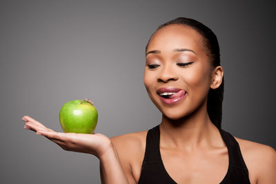 Close-up of woman holding apple against black background