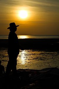 Silhouette of people on beach at sunset