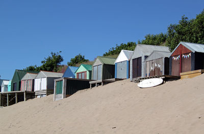 Houses on beach by buildings against clear blue sky