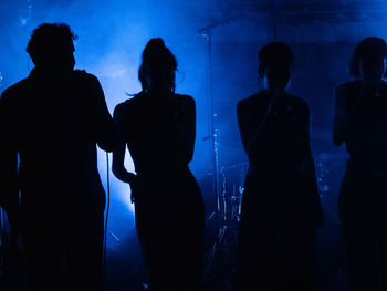 Rear view of silhouette people standing against blue sky