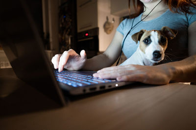 Midsection of woman using laptop with dog