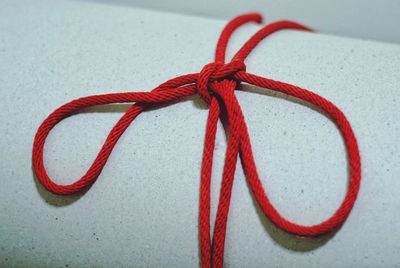 Close-up of red ribbon tied on paper