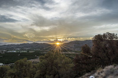 Idyllic view of landscape against cloudy sky during sunset