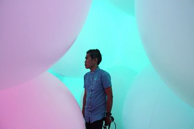 Man standing amidst balloons in art gallery