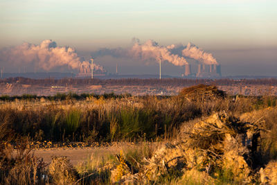 Smoke emitting from factory against sky