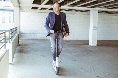 Mature businessman riding e-scooter in parking garage